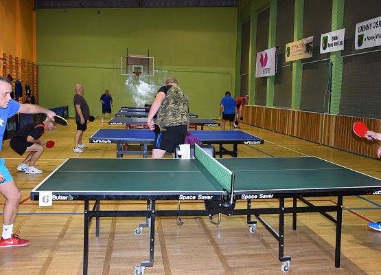 W sali gimnastycznej mężczyźni grają w tenisa stołowego. grafika