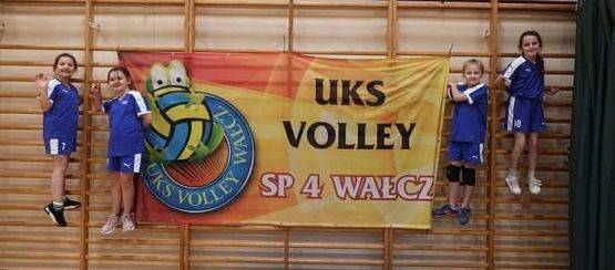 Zawodniczki i zawodnicy na drabinkach w hali sportowej, przy banerze promującym turniej w Wałczu.