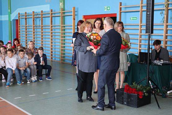 Dyrektor szkoły wręcza nauczycielom kwiaty podczas uroczystości z okazji Dnia Edukacji Narodowej w szkole w Łebieniu..