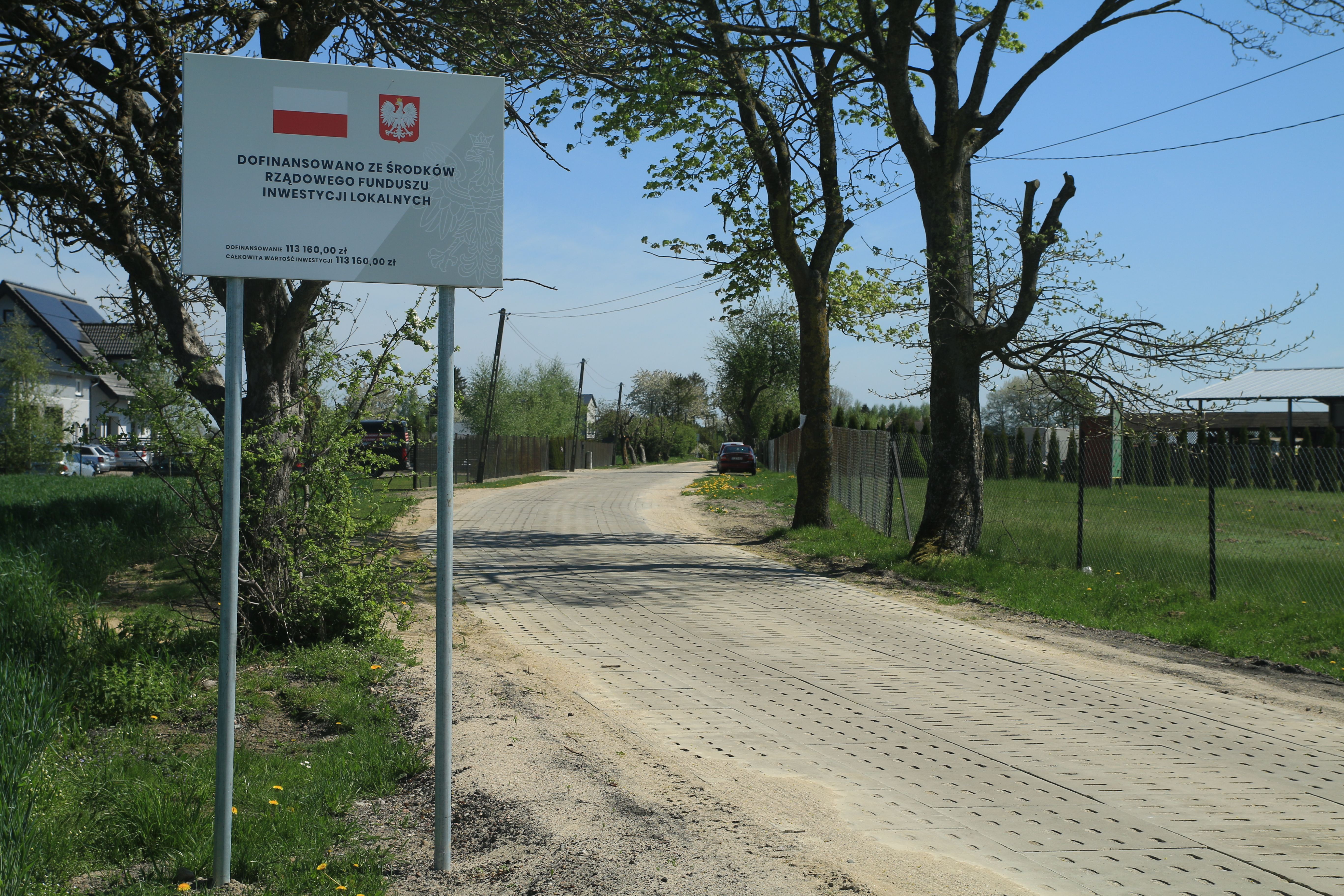 Przebudowana droga w Krępie Kaszubskiej. Płyty typu YOMB. Na pierwszym planie tablica informacyjna o dofinansowaniu z RFIL