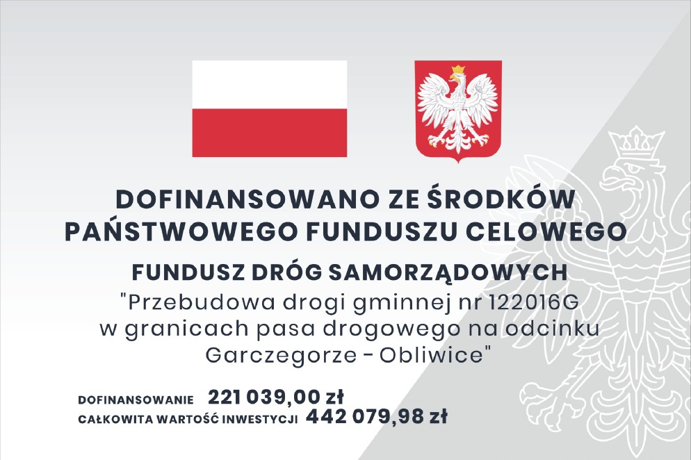 Tablica informacyjna zawierająca nazwę projektu i komunikat o dofinansowaniu inwestycji z Funduszu Dróg Samorządowych. Na tablicy znajduje się flaga i godło Polski.
