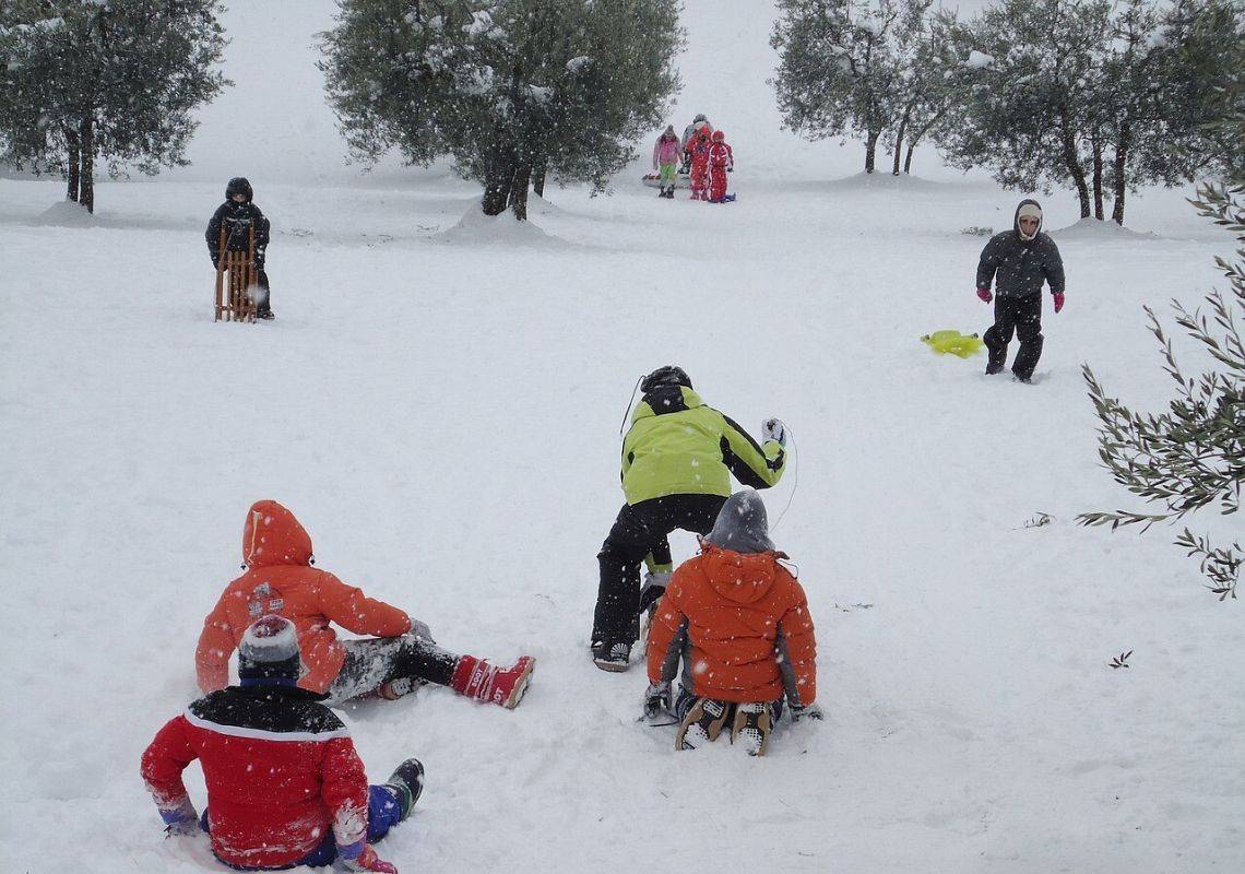 Grupa dzieci bawiących się na śniegu.