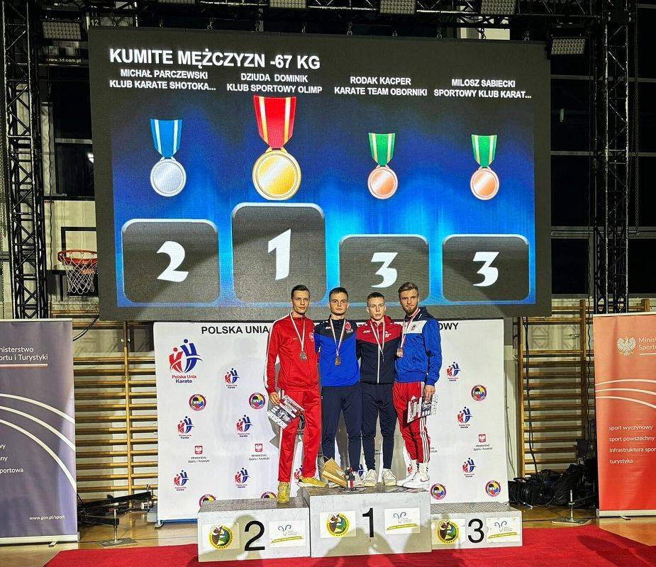 4 mężczyzn stoi na podium z medalami i dyplomami.