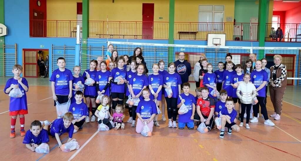 Spotowcy i uczestnicy pozują w hali sportowej do wspólnego, pamiątkowego zdjęcia.