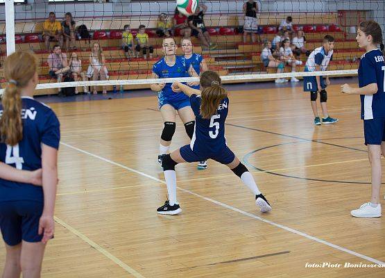 Dziewczęta w trakcie gry w piłkę siatkową w hali sportowej.