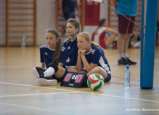 Dziewczęta siedzące na podłodze, z uwagą obserwujące  rozgrywki.