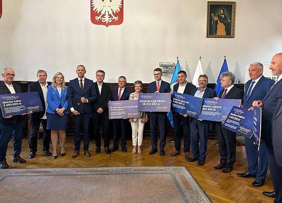 Minister Piotr Müller wręcza promesy na realizację inwestycji w ramach kolejnej edycji Rządowego Funduszu Polski Ład. Wspólne zdjęcie z przedstawicielami wszystkich samorządów Powiatu Lęborskiego.