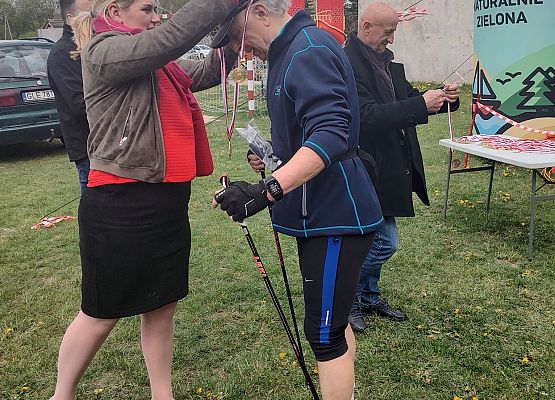 Zastępca Wójta dekoruje medalem jednego z zawodników na mecie.