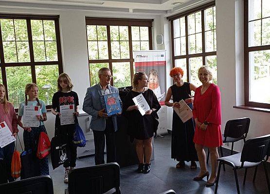 W sali muzeum wójt wręcza upominki.