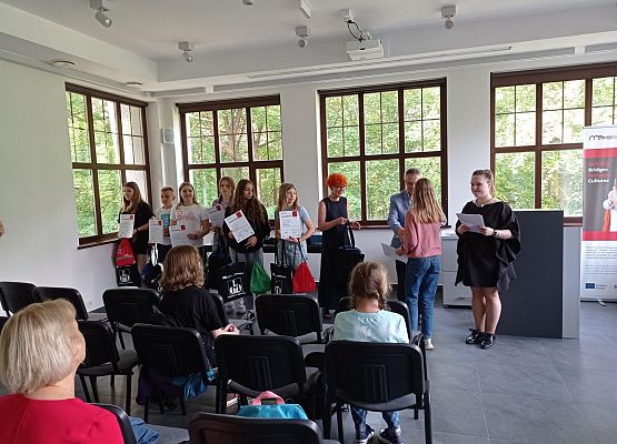 W sali muzeum wójt wręcza upominki.