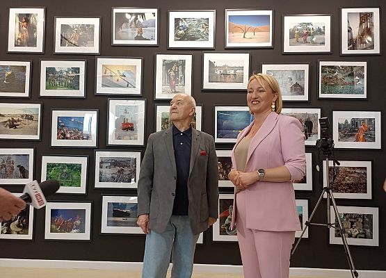 Jacek Pałkiewicz i dyrektor szkoły w Mostach na tle ściany ze zdjęciami z podróży.
