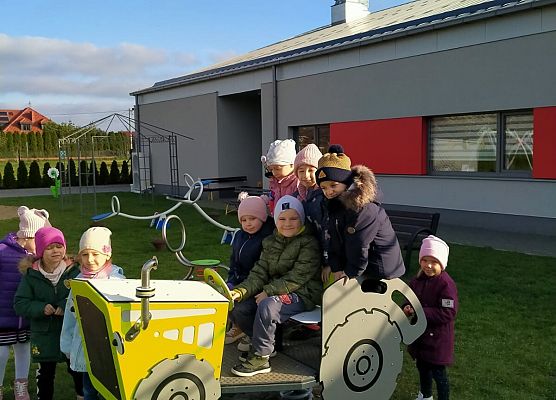 Przedszkolaki ustawione przy zabawkach na placu przy przedszkolu.