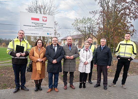 Uczestnicy odbioru przy tablicy informacyjnej inwestycji.