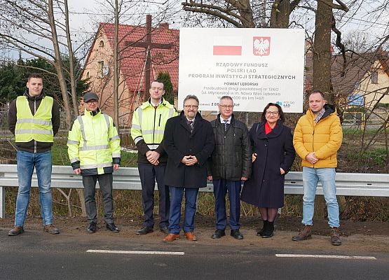 Inwestorzy i wykonawcy stoją przy tablicy informacyjnej inwestycji.