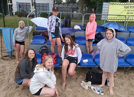 Drużyna dziewczyn po meczu siedzi na trybunach i na piasku.