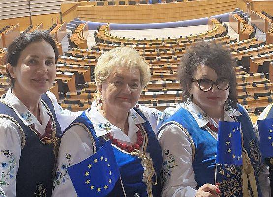 Kobiety w regionalnych strojach pozują do zdjęcia w sali obrad Parlamentu Europejskiego.