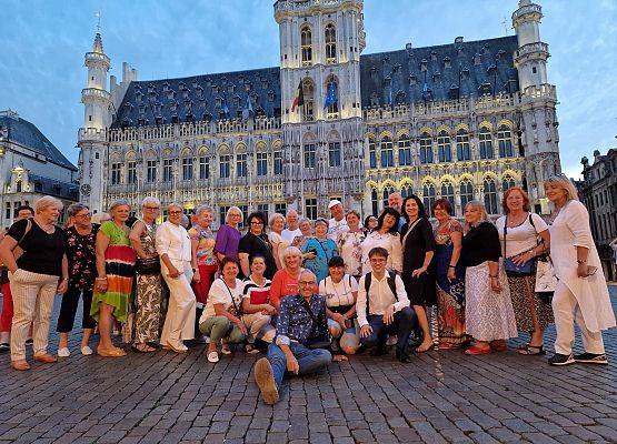Grupa uczestników wycieczki pozuje do zdjęcia na Wielkim Placu w Brukseli.
