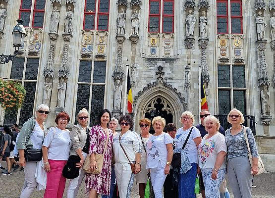 Grupa uczestników wycieczki pozuje do zdjęcia na tle zabytkowej budowli.