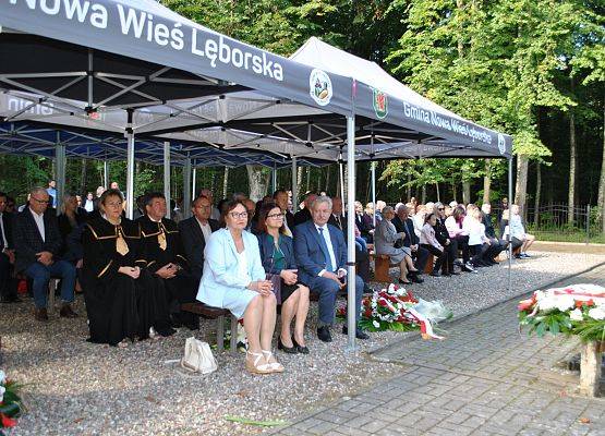 Zaproszeni goście siedzą na ławkach pod namiotem, na placu cmentarza w Krępie Kaszubskiej.