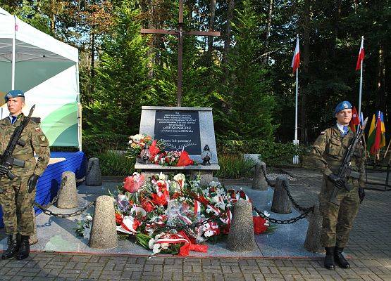 Warta honorowa przy pomniku zbiorowym pomordowanych więźniów na cmentarzu w Krępie Kaszubskiej. Pomnik obłożony wiązankami i wieńcami kwiatów.
