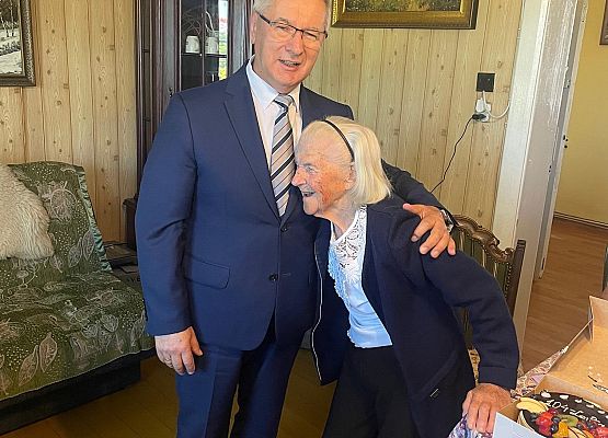 Wójt gminy i jubilatka pozują do zdjęcia.