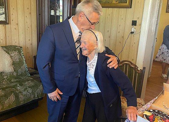 Wójt gminy i jubilatka pozują do zdjęcia.