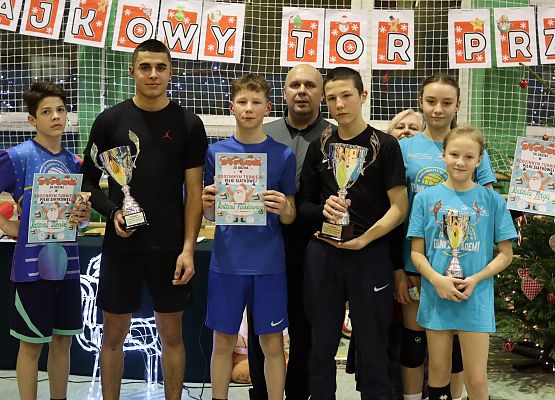 Młodzież z    turnieju pozują do wspólnego zdjęcia w sali gimnastycznej.