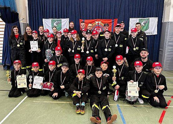 Nagrodzeni młodzi strażacy pozują do zadjęcia z dyplomami i pucharami.