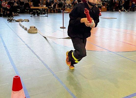 Zawodnik biegnie w wężem strażackim.