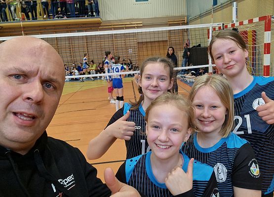 Trener z zawodniczkami pozują do zdjęcia.