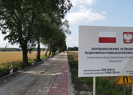 Tablica informacyjna. Przebudowywana droga w tle.