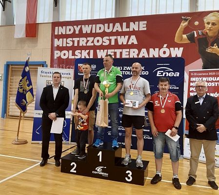 Zwycięzcy turnieju tenisa stołowego, z medalami i nagrodami na podium. grafika