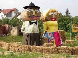 Dekoracja dożynkowa. Dwie postacie, baba i chłop z balotów słomy w odświętnych strojach. grafika