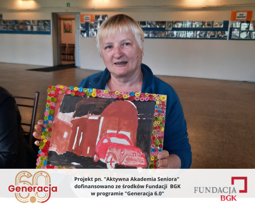 Kobieta prezentująca swoją pracę plastyczną.