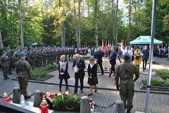 Dyrektor Muzeum w Sztutowie z uczennicami szkoły podstawowej w Garczegorzu składają znicze.