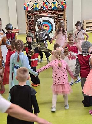 Dzieci tańczą na balu trzymając się za ręce.