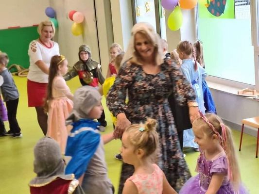 Dzieci tańczą na balu z  trzymając się za ręce.