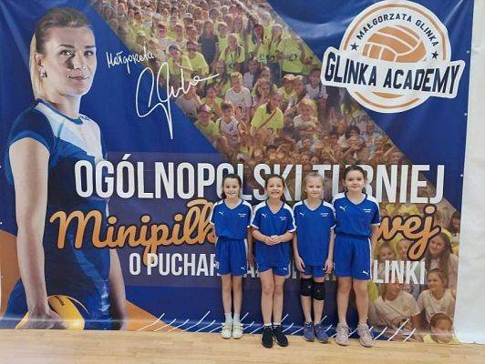 Cztery uśmiechnięte dziewczynki pozują do zdjęcia.