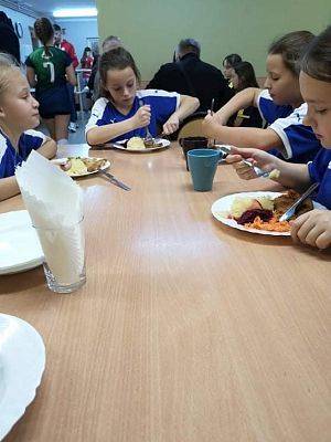 Zawodnicy i zawodniczki przy stole, podczas posiłku.