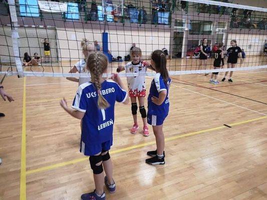 Dwie dziewczynki w trakcie gry w piłkę siatkową w hali sportowej.