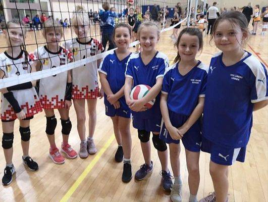 Dwie drużyny dziewcząt pozują do zdjęcia po zakończonym meczu.