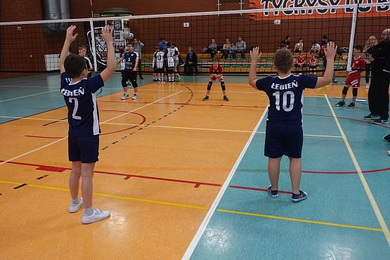 Chłopcy podczas gry w piłkę siatkową w hali sportowej.