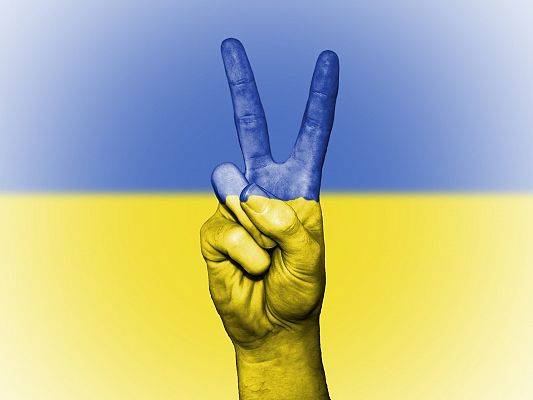 Tło oraz dłoń ułożona w geście zwycięstwa w barwach ukraińskich. grafika