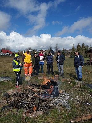 Uczestnicy akcji sprzątania świata przy ognisku smażą kiełbaski.