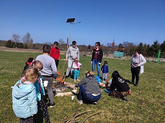 Uczestnicy akcji sprzątania świata przy ognisku smażą kiełbaski.
