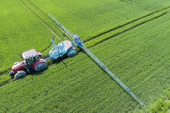 Traktor na polu podczas nawożenia. grafika