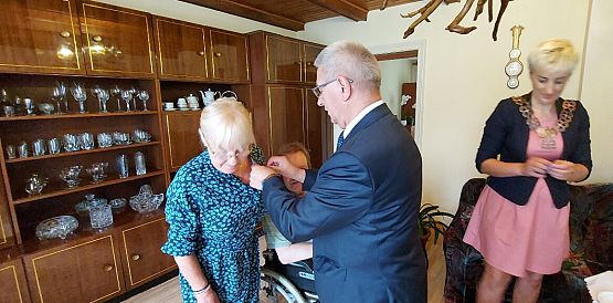 Wójt odznacza medalem jubilatkę.