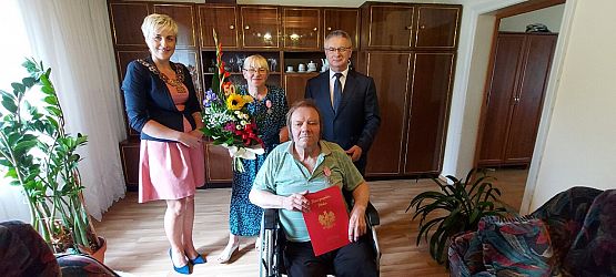 Wspólne zdjęcie jubilatów, wójta i kierownika usc w domu jubilatów.