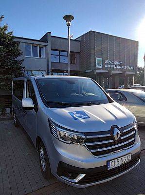 Nowy samochód na tle budynku urzędu gminy. Ujęcie z przodu. grafika