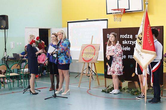 Zastępca Wójta wręcza kwiaty dyrektor szkoły podczas uroczystości z okazji Dnia Edukacji Narodowej w szkole w Redkowicach.
